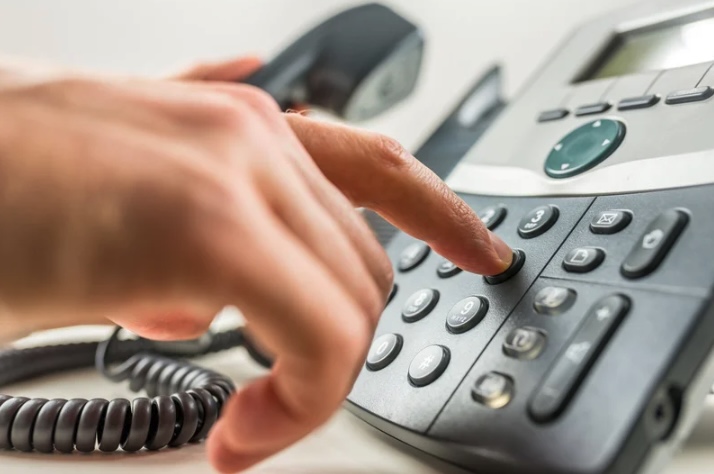 A business professional dialing a desk phone in an office in Ocean County, New Jersey — representing local businesses using AmeriTel’s hosted VoIP and business phone systems.